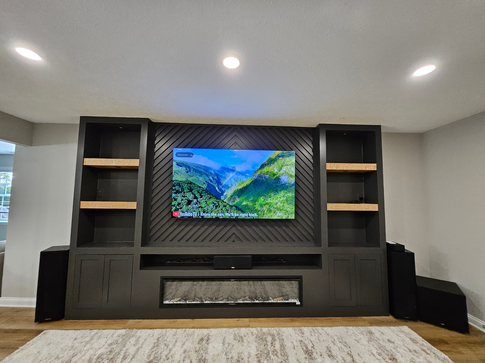 Basement remodel featuring built-in AV system, mounted display, and entertainment area