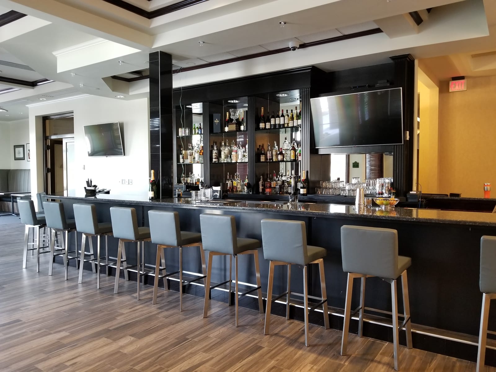 Private country club bar with multiple wall-mounted televisions and ceiling-recessed audio