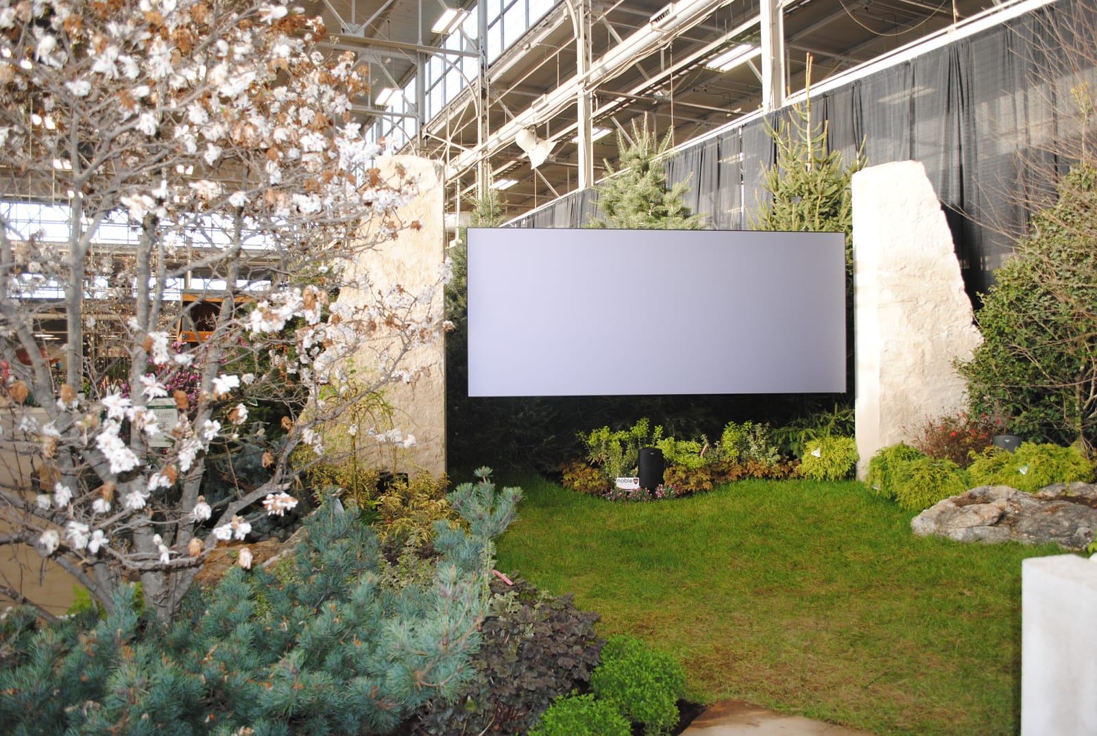 Outdoor flat-panel display mounted between stone columns in a landscaped setting at the Indianapolis Home Show