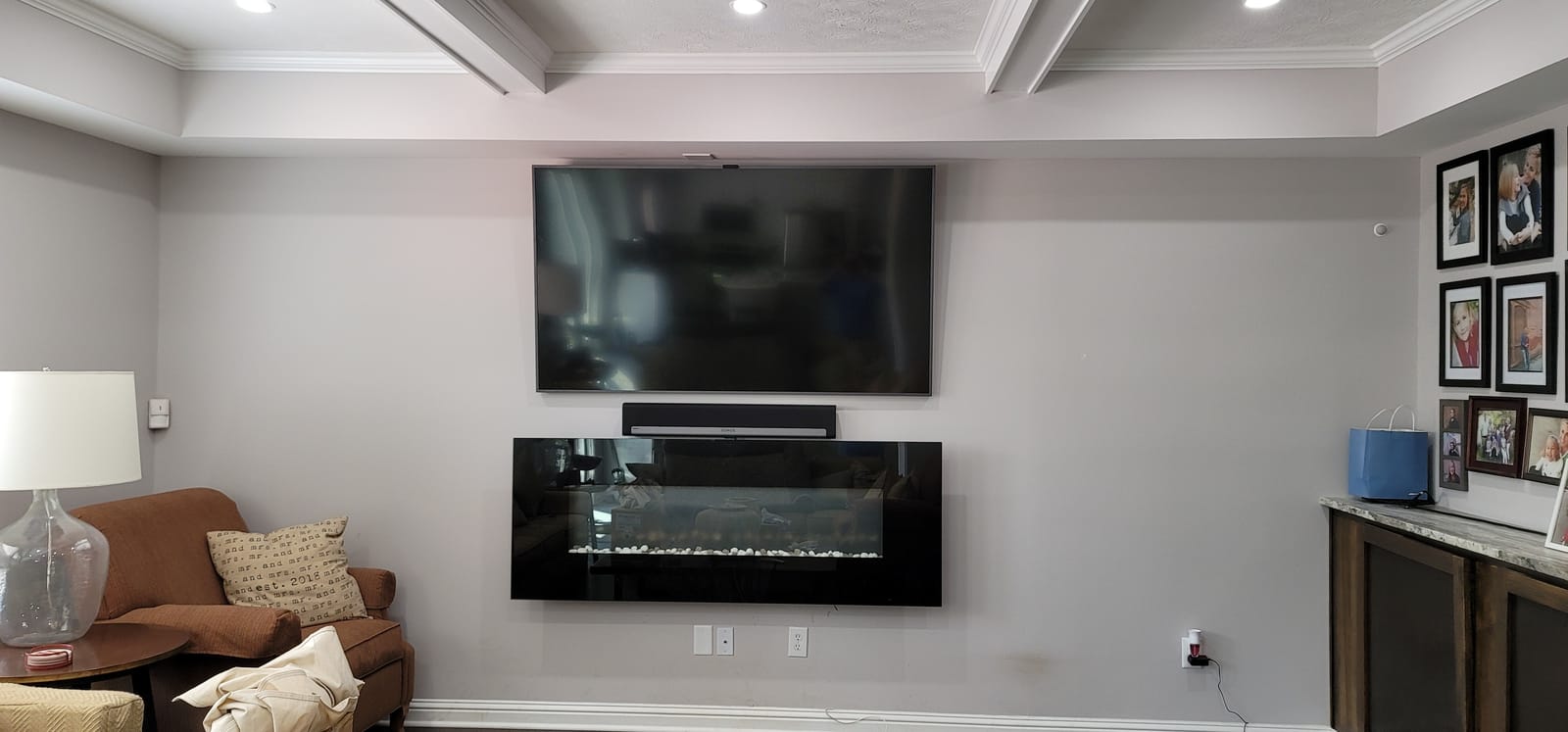 Television installed above a modern linear gas fireplace in a contemporary living room