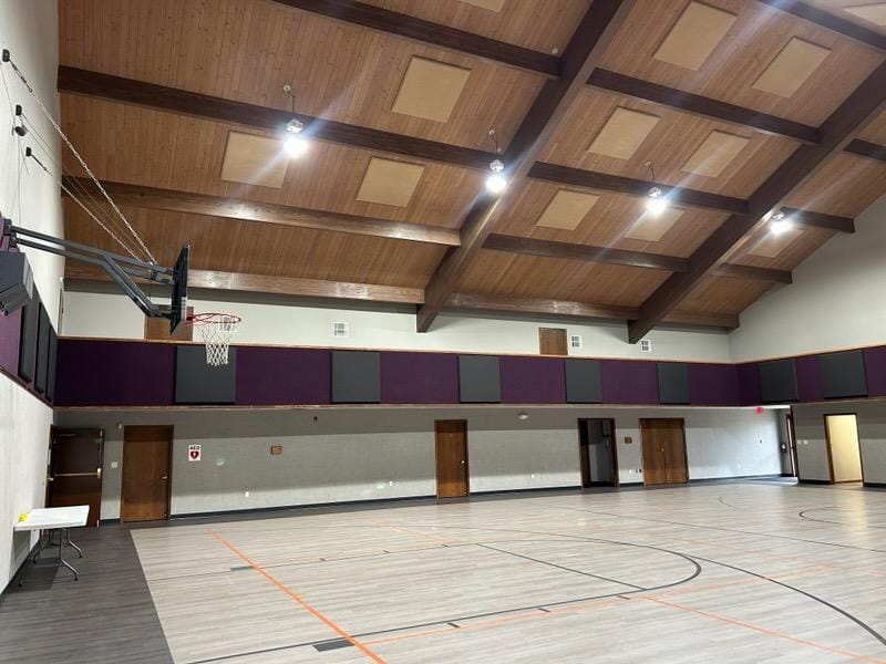 Wide view of worship gymnasium with installed acoustic panels along the upper walls and basketball court below