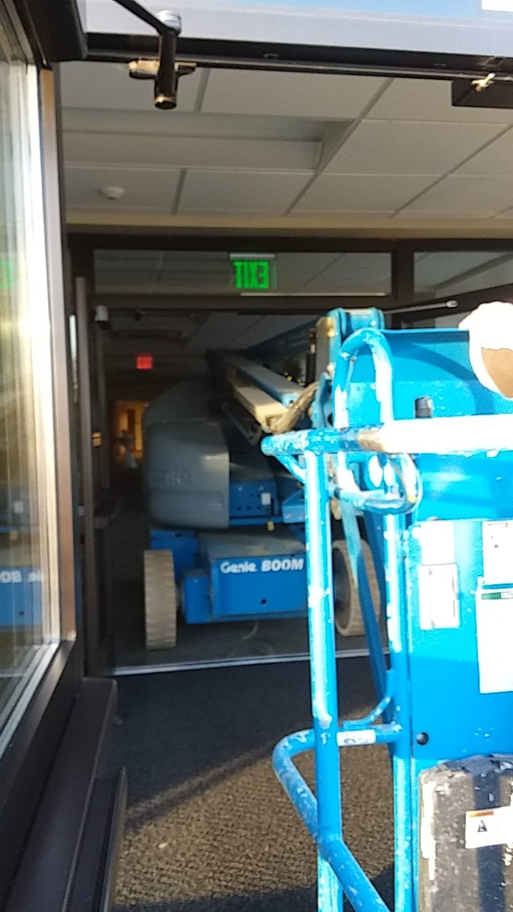Scissor lift positioned at building entry for high-ceiling AV installation work at a house of worship